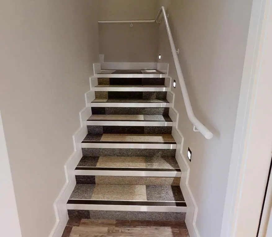 Staircase with patchwork carpet-tile treads and risers, light nosings and dark contrast strips on each step at Abbey House Dental